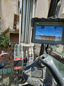 Модерен багер на PardBuild с 2D машинен контрол извършва терасиране на дворове в София.